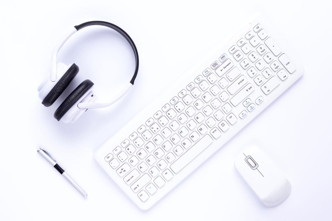 Wireless keyboard, computer mouse, headphones, and desk accessories on a clean white background.
